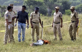 Police personnel stand next to the body of a man at the site where Police officers shot dead four detained gang-rape and murder suspects in Shadnagar, some 55 kilometres (34 miles) from Hyderabad, on December 6, 2019. - Indian police on December 6 shot dead four detained gang-rape and murder suspects as they were re-enacting their alleged crime, prompting celebrations but also accusations of extrajudicial killings.  The men, who had been in custody for a week over the latest gruesome case of violence against women to shock India, were shot in the early morning as they tried to escape during the staged re-enactment in Hyderabad, police said. (Photo by STR / AFP)