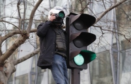 A journalist standing on a traffic sign takes pictures during a march in Paris on December 10, 2019 on a sixth day of a strike of public transport operators SNCF and RATP employees over French government's plan to overhaul the country's retirement system. - Unions have vowed to keep up the fight over the reforms, which are set to be finalised and published on December 11. Another mass demonstration is planned in Paris and other cities today, with teachers and other workers once again expected to walk out alongside transport workers. (Photo by Zakaria ABDELKAFI / AFP)