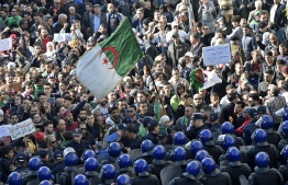 Algerian security surround protesters during an anti-government demonstration in the capital Algiers on December 11, 2019, ahead of the presidential vote scheduled for December 12. - Algeria's contentious presidential election campaign is highlighting the vast gap between youth at the heart of a reformist protest movement and an ageing elite they see as clinging to power. The poll will see five candidates, all linked to ex-president Abdelaziz Bouteflika, compete for the top office. But protesters, whose mass mobilisation forced the ex-strongman to resign from his two-decade tenure in April, have rallied weekly to say sweeping reforms must come ahead of any vote. (Photo by RYAD KRAMDI / AFP)