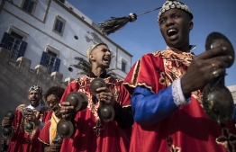 A Gnawa traditional group performs in the city of Essaouira on December 14, 2019, to celebrate the decision of adding the Gnawa culture to UNESCO's list of Intangible Cultural Heritage of Humanity. - Gnawa culture, a centuries-old Moroccan practice rooted in music, African rituals and Sufi traditions, was added to UNESCO's list of Intangible Cultural Heritage of Humanity earlier in the week. Gnawa refers to a "set of musical productions, fraternal practices and therapeutic rituals where the secular mixes with the sacred", according to the nomination submitted by Morocco. Often dressed in colourful outfits, Gnawa musicians play the guenbri, a type of lute with three strings, accompanied by steel castanets called krakebs. (Photo by FADEL SENNA / AFP)