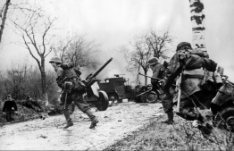 (FILES) This file photograph taken on December 16, 1944,  from a captured German's film, provided on December 27, 1944, shows German infantrymen crossing a road somewhere on the western Front during their drive into the US lines during The Battle of The Bulge - The Ardennes Counteroffensive, in western Belgium. - The Battle of the Bulge was the last German offensive of World War II, and the Siege of Bastogne the scene of a heroic defence by US paratroopers. Seventy-five years later the Belgian town is hosting a weekend of colourful re-enactments followed by solemn ceremonies of remembrance. Veterans, historians and military enthusiasts will join international officials to mark the now legendary close quarters battle on a snowbound wooded plateau. Bastogne's relief in late December 1944 by General George "Old Blood and Guts" Patton helped seal his reputation as one of America's military giants. (Photo by STR / OWI / AFP)