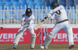 Pakistan's Azhar Ali (R) plays a shot as Sri Lanka's wicketkeeper Niroshan Dickwella looks on during the fifth and final day of the first Test cricket match between Pakistan and Sri Lanka at the Rawalpindi Cricket Stadium in Rawalpindi on December 15, 2019. (Photo by Aamir QURESHI / AFP)