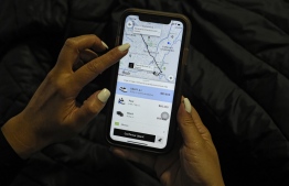 A woman checks the Uber transport application on her mobile phone after authorities ordered its suspension in Colombia, in Bogota on December 20, 2019. (Photo by Juan BARRETO / AFP)
