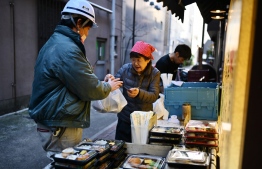A worker buys 'bento', a typical Japanese packed box meal comprised of rice or noodles with fish or meat, and vegetables with pickles, in Tokyo's Nihonbashi area on December 20, 2019. (Photo by CHARLY TRIBALLEAU / AFP)