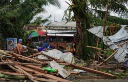 A resident looks at a house damaged at the height of Typhoon Phanfone in Tacloban, Leyte province in the central Philippines on December 25, 2019. - Typhoon Phanfone pummelled the central Philippines on Christmas Day, bringing a wet and miserable holiday season to millions in the mainly Catholic nation. (Photo by Bobbie ALOTA / AFP)
