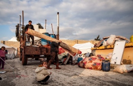 Syrians, among those who fled from government forces' advance on Maaret al-Numan in the south of Idlib prvoince, unload a rolled-up carpet from a truck at a camp for the displaced near the town of Dana in the province's north near the border with Turkey, on December 27, 2019. (Photo by Aaref WATAD / AFP)