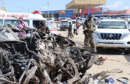 A soldier is seen next to the wreckage of car that was damaged during the car bomb that exploded in Mogadishu that killed more than 20 people is photographed in Mogadishu on December 28, 2019. - A massive car bomb exploded in a busy area of the Somali capital Mogadishu on December 28, 2019, leaving more than 20 people dead. (Photo by Abdirazak Hussein FARAH / AFP)