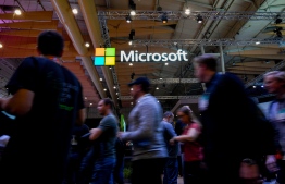 (FILES) In this file photo taken on November 6, 2019 Attendees walk past the logo of US multinational technology company Microsoft during the Web Summit in Lisbon. Microsoft said on December 30, 2019 it obtained a court order allowing it to seize web domains used by North Korean hacking groups to launch cyberattacks on human rights activists, researchers and others. The US technology giant said a federal court allowed it to take control of 50 domains operated by a group dubbed Thallium, which tricked online users by fraudulently using Microsoft brands and trademarks.