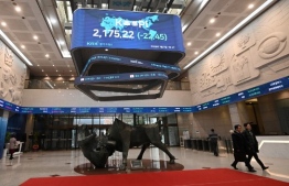 People walk past a screen showing South Korea's benchmark stock index at the lobby of the Korea Exchange in Seoul on January 2, 2020. (Photo by Jung Yeon-je / AFP)