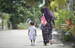 (FILE) A woman and a child walk down a street in Kanduhulhudhoo, Gaafu Alif Atoll. -- Photo: Nishan Ali / Mihaaru