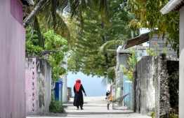 A child walks alongside a guardian in Kanduhulhudhoo, Gaafu Alif Atoll. PHOTO: NISHAN ALI