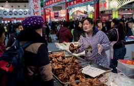 A vendor (R) sells meat at a market in Beijing on January 15, 2020. - China's trade surplus with the United States narrowed last year as the world's two biggest economies exchanged punitive tariffs in a bruising trade war, official data showed. (Photo by NICOLAS ASFOURI / AFP)