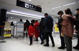 Passengers who arrived on one of the last flights from the Chinese city of Wuhan walk through a health screening station at Narita airport in Chiba prefecture, outside Tokyo, on January 23, 2020, as countries screen for anyone showing symptoms of a SARS-like virus which has killed at least 17 people and infected over 500. (Photo by CHARLY TRIBALLEAU / AFP)