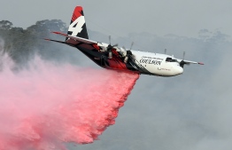 (FILES) This file photo taken on January 10, 2020 shows a C-130 Hercules plane from the New South Wales Rural Fire Service dropping fire retardent to protect a property during an operation to douse bushfires in Penrose, in Australia's New South Wales state. - Three people died when a C-130 Hercules water-bombing plane crashed southwest of Sydney on January 23, 2020, setting off a "large fireball", Australian officials said, as bushfires flared across the country's southeast. (Photo by SAEED KHAN / AFP)