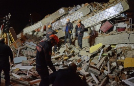 Turkish rescue and police work at the scene of a collapsed building following a 6.8 magnitude earthquake in Elazig, eastern Turkey on January 24, 2020. - A powerful earthquake with a magnitude of 6.8 hit eastern Turkey, killing at least four people, causing buildings to collapse and sending panicked residents rushing into the street. Rescue teams were being sent to the scene of the quake, which had its epicentre in the small lakeside town of Sivrice in the eastern province of Elazig. (Photo by ILYAS AKENGIN / Demiroren News Agency (DHA) / AFP)