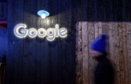 A man passes by a sign of Google at Google's stand during the annual meeting of the World Economic Forum (WEF) in Davos, on January 21, 2020. (Photo by Fabrice COFFRINI / AFP)