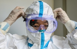 This photo taken on January 30, 2020 shows a doctor putting on a pair of protective glasses before entering the isolation ward at a hospital in Wuhan in China's central Hubei province, during the virus outbreak in the city. - The World Health Organization declared a global emergency over the new coronavirus, as China reported January 31 the death toll had climbed to 213 with nearly 10,000 infections. (Photo by STR / AFP) / 