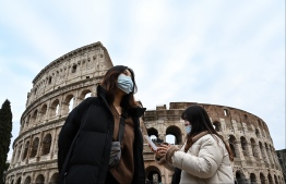Tourists wearing protective respiratory masks tour outside the Colosseo monument (Colisee, Coliseum) in downtown Rome on January 31, 2020. - The Italian government declared a state of emergency on January 31 to fast-track efforts to prevent the spread of the deadly coronavirus strain after two cases were confirmed in Rome. (Photo by Alberto PIZZOLI / AFP)