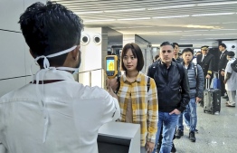 In this handout photograph taken and released by the Ministry of Civil Aviation (MoCA) on January 21, 2020, a man (L) uses a thermographic camera to screen the head of people at Netaji Subhash Chandra Bose International Airport in Kolkata, following the Ministry of Health and Family Welfare's advisory to screen passengers arriving in India from China and Hong Kong regarding the novel coronavirus (nCoV) issue.  (Photo by Handout / Ministry of Civil Aviation (MoCA) / AFP) 