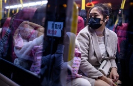 A mask-clad bus passenger looks out her window during a strike at the Hospital Authority building in Hong Kong on February 7, 2020, calling for the government to close its border with mainland China to contain the new coronavirus epidemic. - Hong Kong on February 7 said it will deploy an army of volunteers to bolster plans to forcibly quarantine all arrivals from mainland China, warning that anyone caught breaching the new rules faces up to six months prison. (Photo by Philip FONG / AFP)