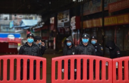 (FILES) This file photo taken on January 24, 2020 shows police officers and security guards standing outside the Huanan Seafood Wholesale Market where the new coronavirus was first detected in Wuhan. - For eight days, starting on January 23, 2020, an AFP team lived and worked at the centre of a global health emergency, witnessing how life in the Chinese city of Wuhan was turned upside down as it was cut off from the world. (Photo by Hector RETAMAL / AFP) / 