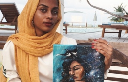 Local artist Samiyya Shehenaaz (Sam) holding up a self-portrait 'Underwater Galaxies' from her 'Youniverse' collection. The artwork displayed at Angsana Velavaru is the artist's second solo exhibition. PHOTO: SAM