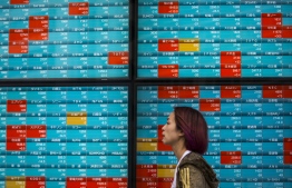 A pedestrian walks past a stock indicator displaying share prices on the Tokyo Stock Exchange in Tokyo on February 3, 2020. - Tokyo stocks dropped on February 3 as the Chinese market plunged after investors returned from an extended holiday during which the new coronavirus outbreak drove down the global market. (Photo by Behrouz MEHRI / AFP)