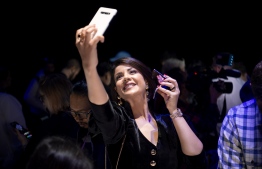 Morrocan actress-model Leila Hadioui takes a selfie while holding a Samsung Galaxy Z Flip phone displayed during the Samsung Galaxy Unpacked 2020 event in San Francisco, California on February 11, 2020. - Samsung unveiled its second folding smartphone, a "Z Flip" handset with a lofty price tag aimed at "trendsetters." The smartphone flips open, like a pocket cosmetics case, opening into a 6.7-inch screen. (Photo by Josh Edelson / AFP)