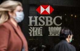 A woman (L) walks past a HSBC sign in Hong Kong on February 18, 2020. - The London-based, Asia-focused behemoth HSBC is expected to release its Q4 and 2019 results later on February 18. (Photo by ISAAC LAWRENCE / AFP)