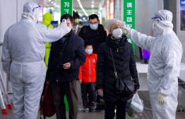 This photo taken on February 18, 2020 shows passengers having their temperature taken as a preventive measure against the COVID-19 coronavirus at a train station in Nanjing, in China's eastern Jiangsu province. - The death toll from China's new coronavirus epidemic jumped past 2,000 on February 19 after 136 more people died, with the number of new cases falling for a second straight day, according to the National Health Commission. PHOTO: STR / AFP