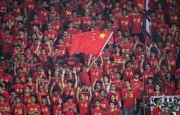 (FILES) This file photo taken on October 10, 2019 shows a fan waving the Chinese national flag as others cheer during the World Cup 2022 qualifier football match between China and Guam in Guangzhou. - The coronavirus exposes an ignorance of China's lucrative sports market and poor contingency planning, experts say, after Formula One became the most high-profile casualty of a mass pullout from the country. PHOTO: STR / AFP