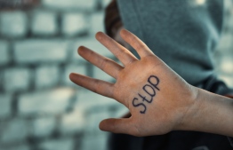 A boy holds up a hand with the word STOP scrawled on his palm, to illustrate the topics of abuse and sexual violence against children. PHOTO/FREEPIK