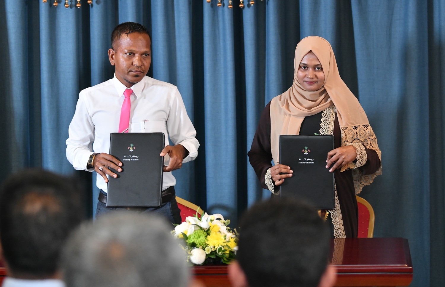 ހެލްތު މިނިސްޓްރީގެ މަޝްރޫއެއް ހިންގުމުގެ އެއްބަސްވުމުގައި ސޮއިކުރެއްވުމަށްފަހު ރަށެއްގެ ކައުންސިލަރަކާއި ސިއްހީ މަރުކަޒުގެ އޮފިޝަލަކު ފޮޓޯއަކަށް ހުއްޓިލައިގެން-- ފޮޓޯ: އަހުމަދު އަވްޝަން އިލްޔާސް/ މިހާރު