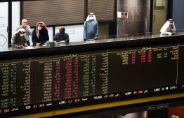 Kuwaiti traders wearing protective masks follow the market at the Boursa Kuwait stock exchange in Kuwait City on March 1, 2020. - Boursa Kuwait decided to close the main trading hall due to the COVID-19 coronavirus disease developments. Stock markets in the oil-rich Gulf states plunged on March 1 over fears of the impact of the coronavirus, which also battered global bourses last week. All of the seven exchanges in the Gulf Cooperation Council (GCC), which were closed the previous two days for the Muslim weekend, were hit as oil prices dropped below $50 a barrel. The region's slide was led by Kuwait Boursa, where the All-Share Index fell 10 percent, triggering its closure. Kuwait's bourse was closed for most of last week for national holidays. (Photo by YASSER AL-ZAYYAT / AFP)