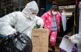 A woman (R), who has recovered from the COVID-19 coronavirus infection, arrives at a hotel for a 14-day quarantine after being discharged from a hospital in Wuhan, in China's central Hubei province on March 1, 2020. - China on March 1 reported 35 more deaths from the new coronavirus, taking the toll in the country to 2,870. (Photo by STR / AFP) / 