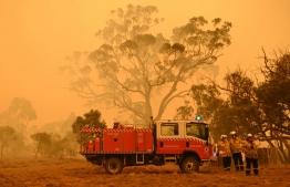 Firefighters protect a property from bushfires burning near the town of Bumbalong south of Canberra on February 1, 2020. - Authorities in Canberra on January 31, 2020 declared the first state of emergency in almost two decades as a bushfire bore down on the Australian capital. (Photo by PETER PARKS / AFP)