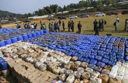 Foreign military attachés check drugs in a football ground where seized drugs, vehicles, laboratory accessories and precursor chemicals are being displayed to be witnessed by invited military attachés and journalists in Kawnghka at Shan State on March 6, 2020. 97 million US dollar worth of drugs and related items were seized this year during a special operation held to crack down drugs trafficking, a military spokesperson said. PHOTO: YE AUNG THU / AFP