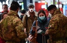 Soldier (L and R) wearing a respiratory mask control passengers arriving at the Milan Centrale railway station on March 9, 2020 as Italy is battling the world's second-most deadly virus outbreak after China and has imposed a virtual lockdown on the north of the country. (Photo by Miguel MEDINA / AFP)