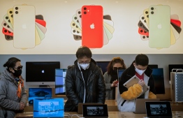 In this picture taken on March 11, 2020 customers wearing face masks as a preventive measure against the COVID-19 coronavirus are seen inside of an Apple shop in Beijing. - The number of fresh infections at the epicentre of China's COVID-19 coronavirus epidemic dropped to a new low on March 12 but the country imported more case from abroad. (Photo by NICOLAS ASFOURI / AFP)