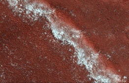 This NASA image released March 12, 2020 shows Mars with an exposed section of the north polar layered deposits (NPLD) looking much like a slice of layered tiramisu, the NPLD is made up of water-ice and dust particles stacked one on top of the other, instead of icing, layers are topped with seasonal carbon dioxide frost, as seen here as lingering frost adhering to one of the layers. - The high-resolution and color capabilities of the Mars Reconnaissance Orbiter's HiRISE camera provides details on the variations in the layers. Scientists are also using radar data, which show us that they have continuity in the subsurface. During deposition, these complex layers might encapsulate tiny air pockets from the atmosphere which, if sampled, could be studied to understand linkages to previous climates. (Photo by Handout / NASA / AFP) / 