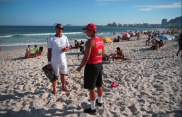 A lifeguard talks to beachgoer on Copacabana beach in Rio de Janeiro, Brazil, on March 16, 2020 when authorities armed with megaphones blared out messages ordering everyone home as a preventive measure against the spread of the new coronavirus, COVID-19. - Rio state Governor Wilson Witzel had warned residents to stay off the beach in order to help contain the pandemic, in a video message on March 13 in which he also announced the closure of schools, cinemas, theatres and large events for at least two weeks. PHOTO: CARL DE SOUZA / AFP