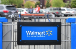 (FILES) In this file photo taken on May 23, 2019 shoppers carry their goods past a shopping cart in the parking lot of a Walmart Supercenter in Rosemead, California. - Walmart announced an emergency leave policy on March 10, 2020 after one of its employees tested positive for the COVID-19 virus, known as Coronavirus in Cynthiana, Kentucky. (Photo by Frederic J. BROWN / AFP)