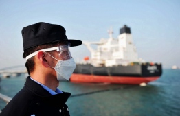 This photo taken on March 20, 2020 shows a police officer wearing a mask amid concerns over the COVID-19 coronavirus while keeping watch as a Kuwaiti oil tanker unloads crude oil at the port in Qingdao, in China's eastern Shandong province. (Photo by STR / AFP) / 