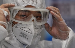 A member of the airport security wearing protective gear as a preventive measure against the COVID-19 coronavirus outbreak monitors passengers as they exit following their arrival at Shanghai Pudong International Airport in Shanghai in March 26, 2020. PHOTO: HECTOR RETAMAL / AFP