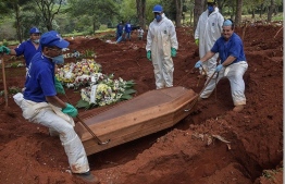 Employees bury a person who died suspectedly from COVID-19 at the Vila Formosa cemetery, in the outskirts of Sao Paulo, Brazil on March 31, 2020. Vila Formosa cemetery, the largest in Latin America with an area of 780 thousand square meters and where more than 1.5 million people were buried, had a 30% increase in the number of burials after the beginning of the COVID-19 pandemic. PHOTO: AFP