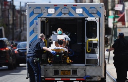 Paramedics transport a patient wearing a face mask to the emergency room entrance of the Wyckoff Heights Medical Center in Brooklyn, New York, on April 2, 2020. PHOTO: AFP