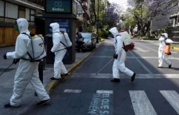 Cleaning workers wearing personal protective equipment disinfect a street in Mexico City amid the COVID-19 outbreak. PHOTO: AFP
