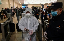 Passengers in protective suits were arriving at Hankou station to board some of the first trains leaving the city. PHOTO; AFP