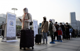 People wearing face masks arrive at Hankou Railway Station in Wuhan to take one of the first trains leaving the city in China's central Hubei province early on April 8, 2020. - Thousands of relieved citizens streamed out of China's Wuhan on April 8 after authorities lifted months of lockdown at the coronavirus epicentre, offering some hope to the world despite record deaths in Europe and the United States. (Photo by NOEL CELIS / AFP)