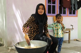 Woman cooking with child nearby. PHOTO: MOHAMED NAAHEE/ UNDP MALDIVES